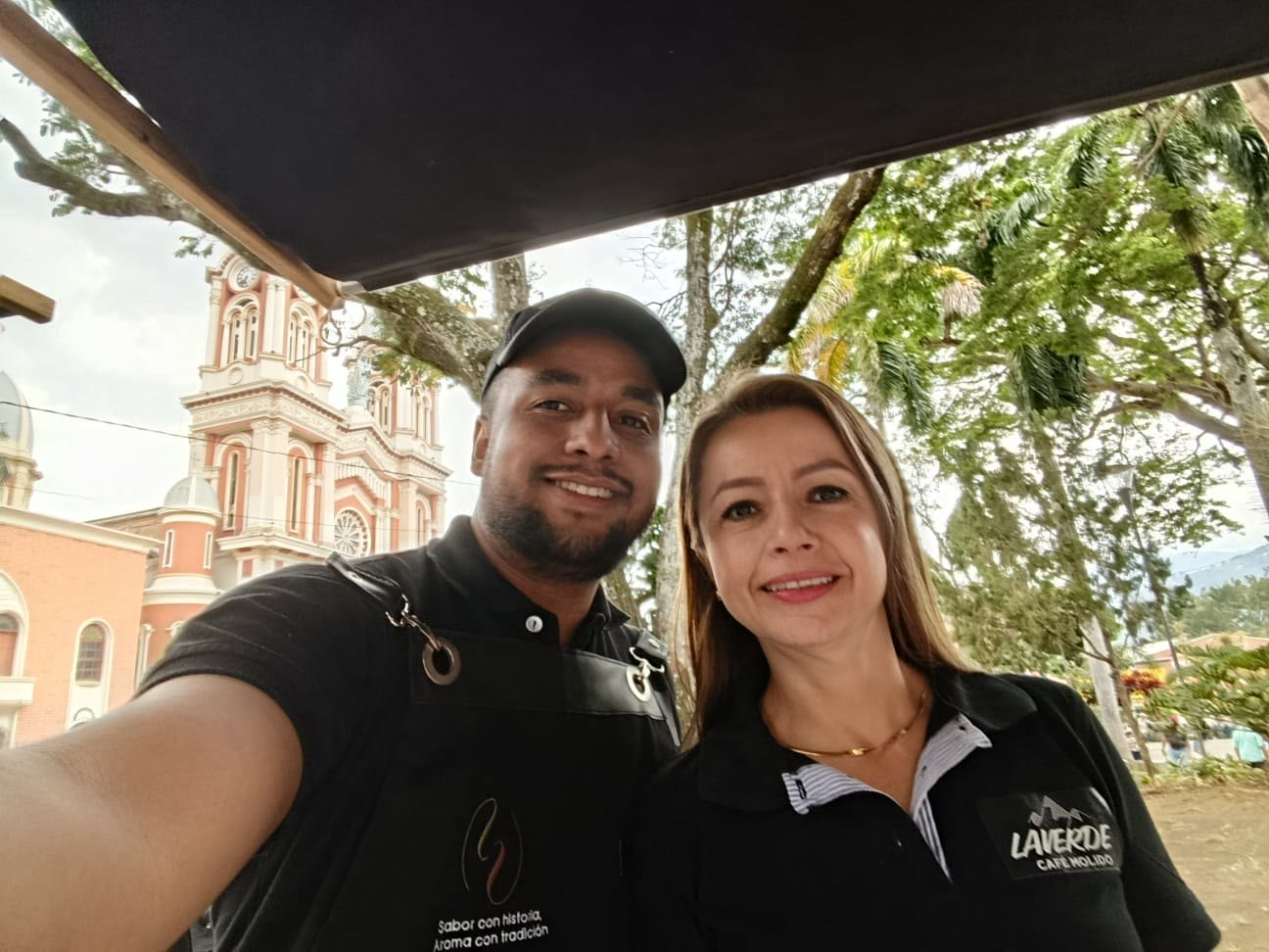 Diana and Diego in the main square of Betulia, Antioquia, with the parish church behind them